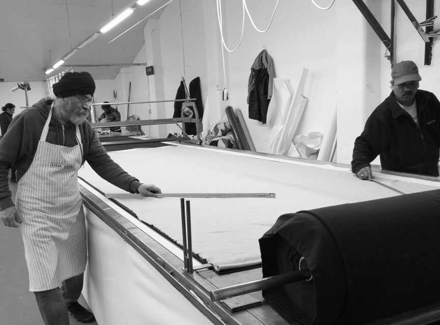 Two garment workers smoothing out fabric in a British factory