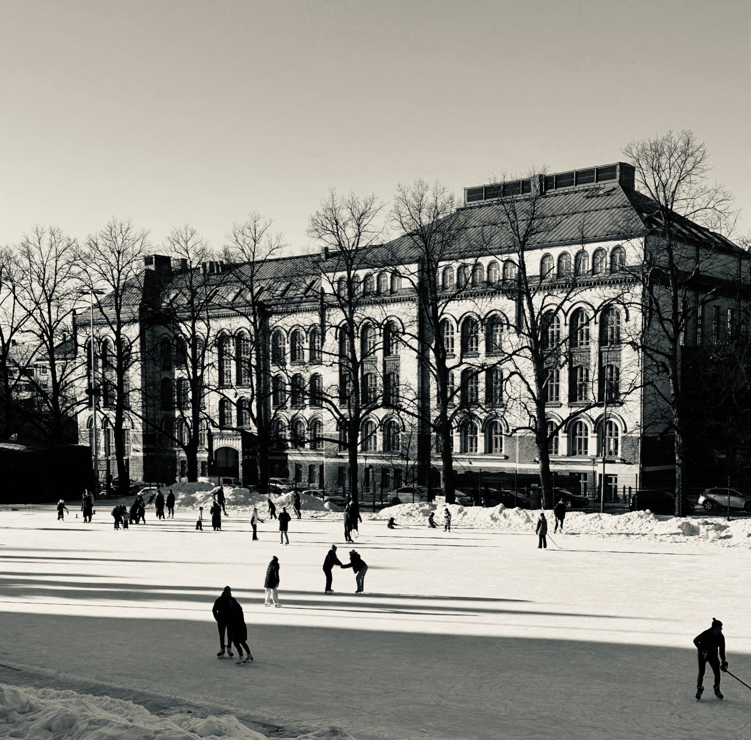 People skating on an outdoor rink in Helsinki with an architectural building in the background
