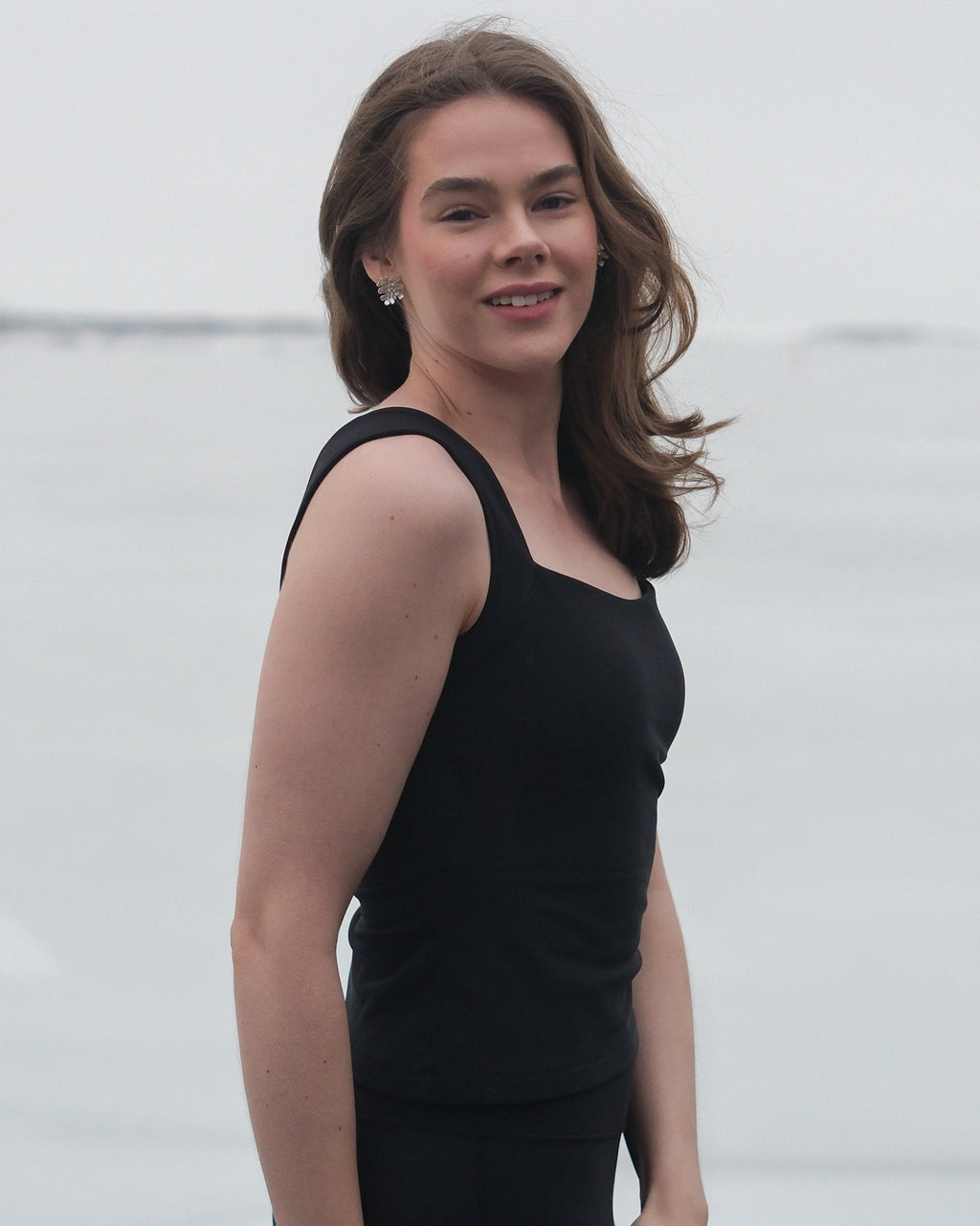 A model standing sideways looking at the camera wearing the Skaet thermal Curve Top