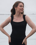 A woman wearing a sleeveless black thermal top with a square neckline and wide straps from the brand Skaet.