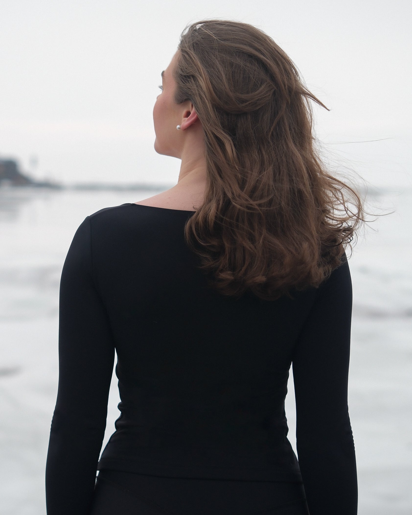A woman wearing a black thermal long-sleeved top with her back towards the camera.