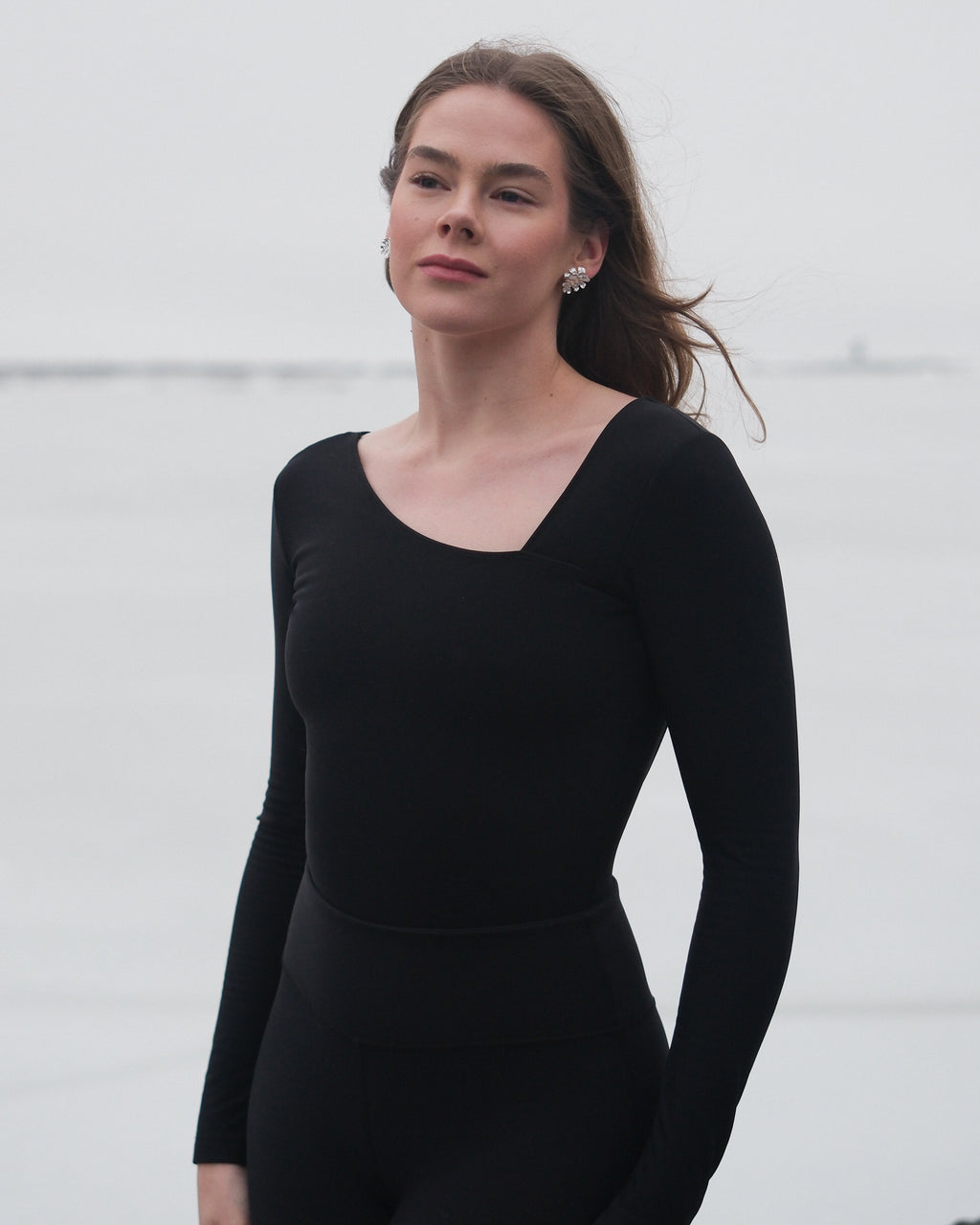 A woman wearing a thermal black bodysuit with an asymmetrical neckline