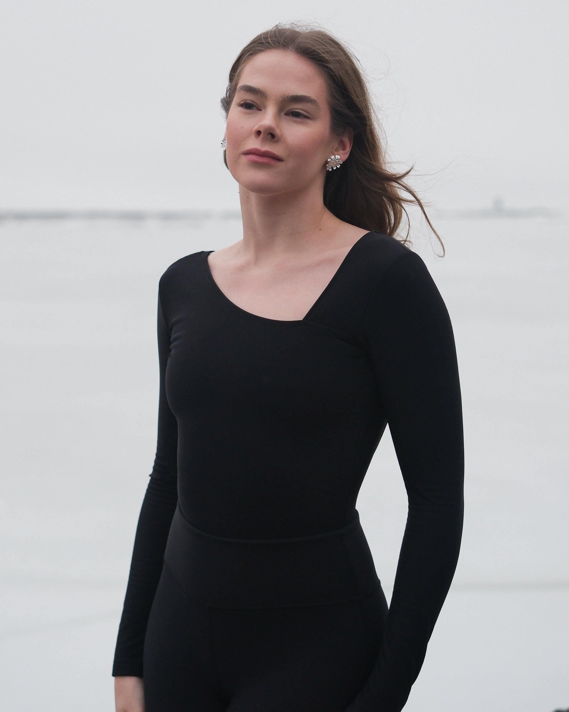 A woman wearing a thermal black bodysuit with an asymmetrical neckline