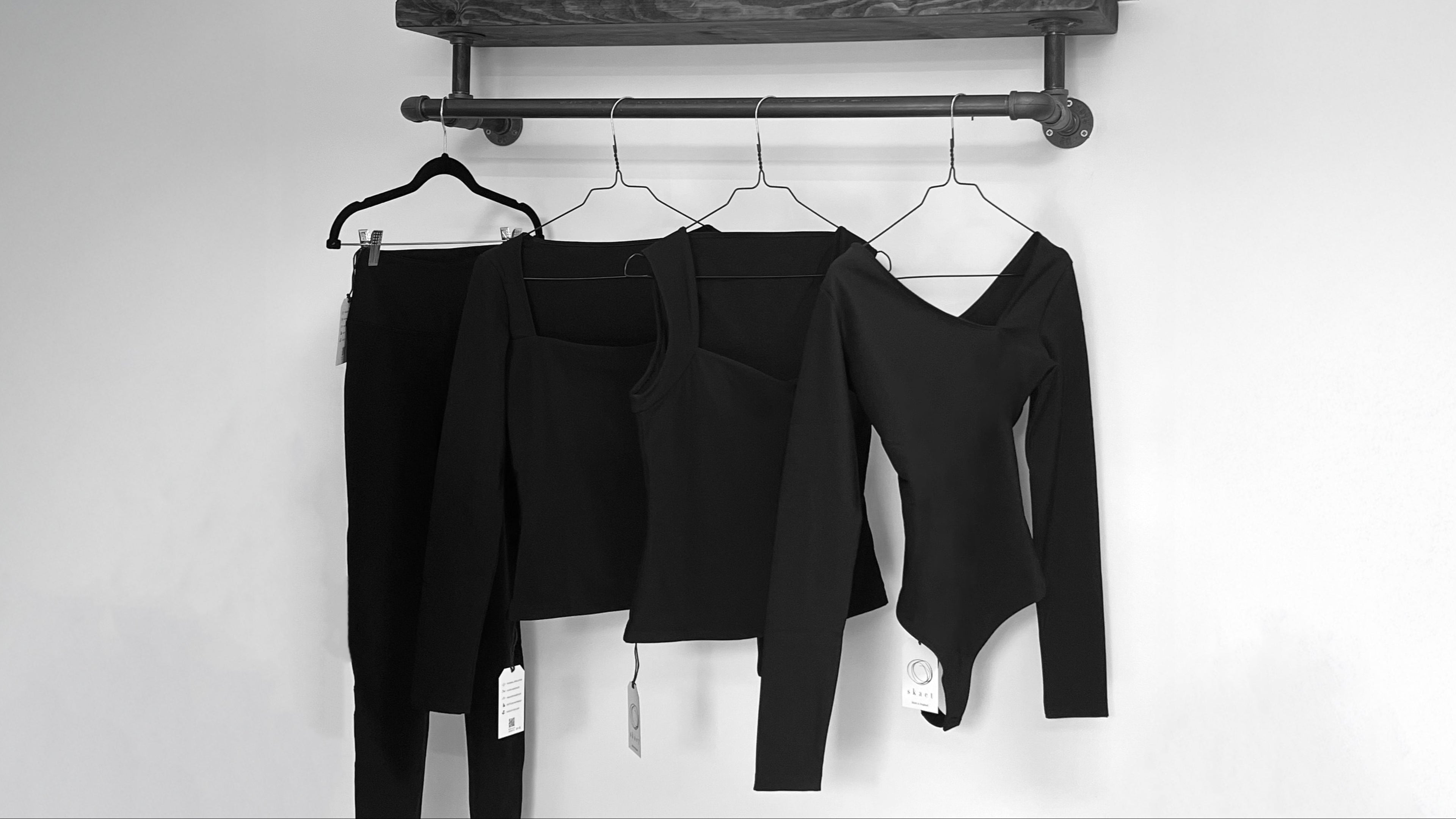 Black thermal clothing items hanging on a rack against a white wall