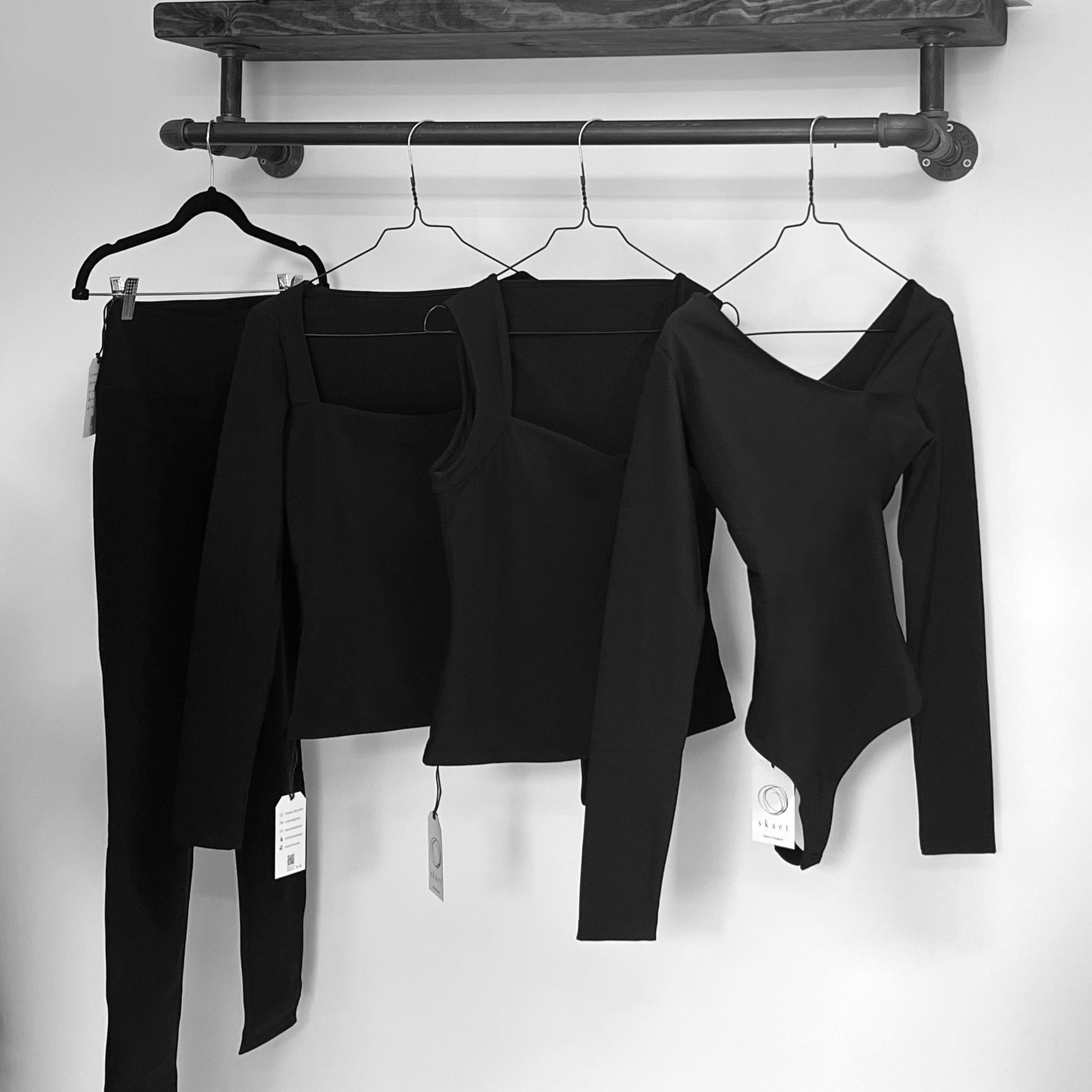 Black thermals hanging on a rail on metal hangers 