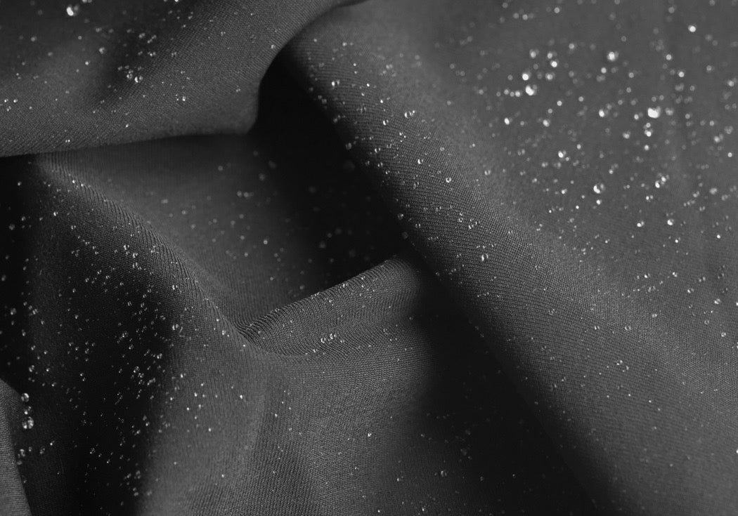 Black water-repellent fabric beautifully folded with water beading on top